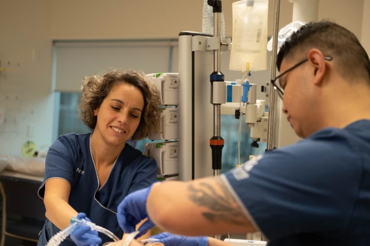 Nurses Cecilia and Sherwin in scrubs preparing some hospital equipment for the next patient.