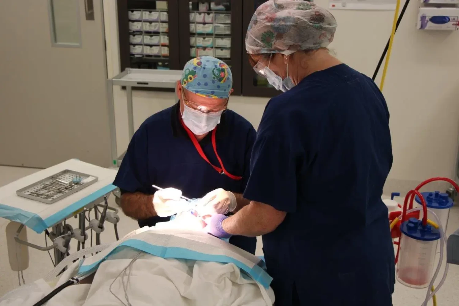 a dental surgeon performs dental surgery in the operating theatre with a theatre nurse assisting