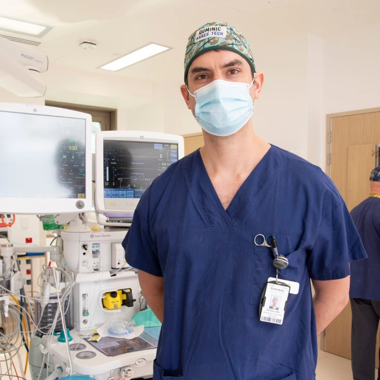 Anaesthetic Technician Dominic standing in front of anaesthetic machines.