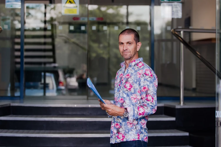 A Health New Zealand healthcare professional stands in front of the entrance at the bottom of the steps