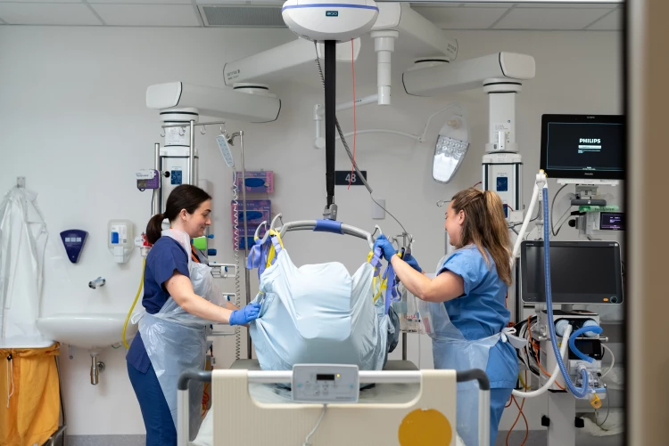 A patient being lifted by two registered nurses on either side