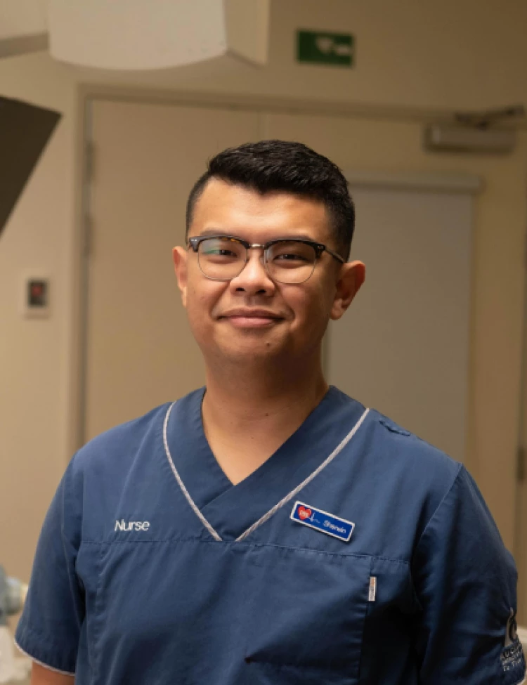 Registered nurse Sherwin in blue scrubs standing in a hospital room