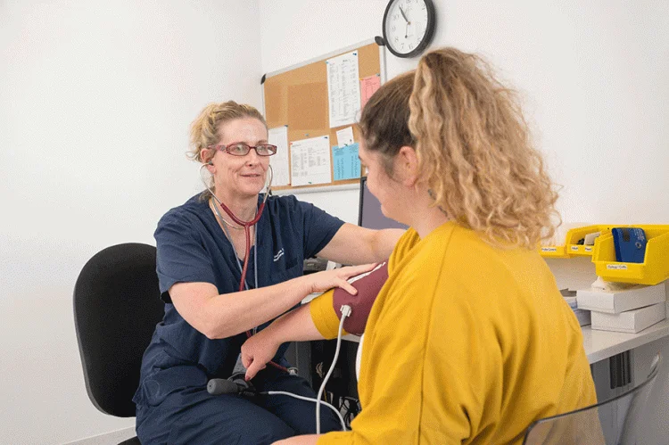 nurse with patient taking blood pressure - source: photoshoot