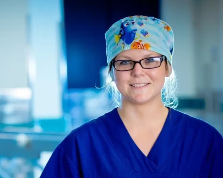 A medical scientist in blue scrubs standing in the hospital laboratory.