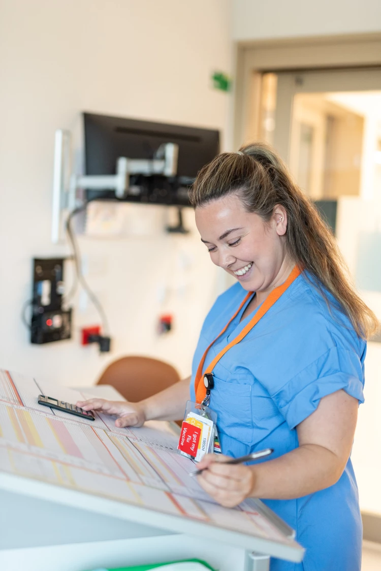 Registered Nurse Rebekah looking over patient records in the nurses' station.