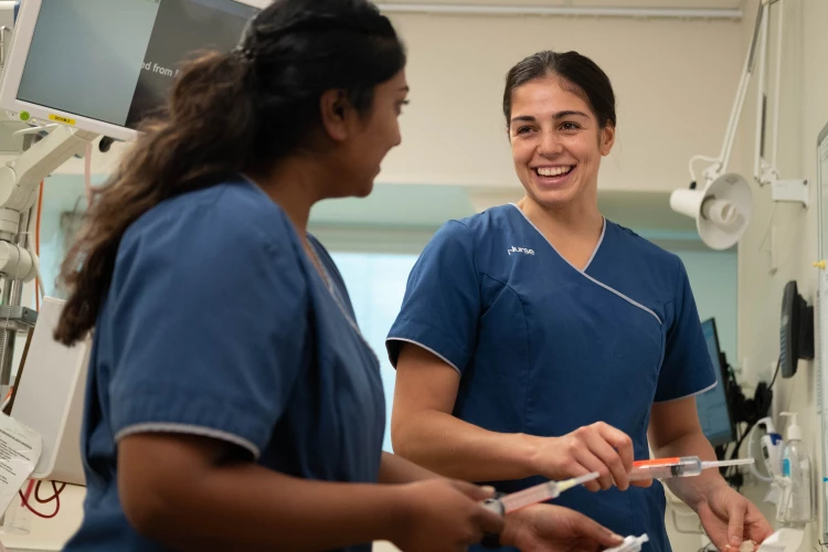 A couple of registered nurses happily chatting away to each other while checking the syringes