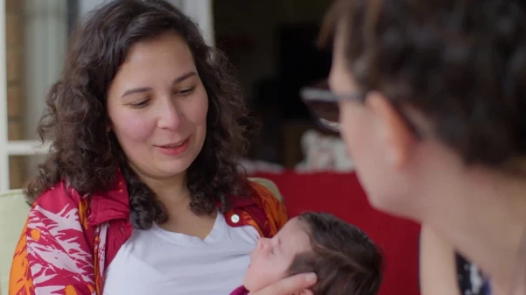 A mother holding a newborn during a Well Child checkup by a New Zealand midwife.